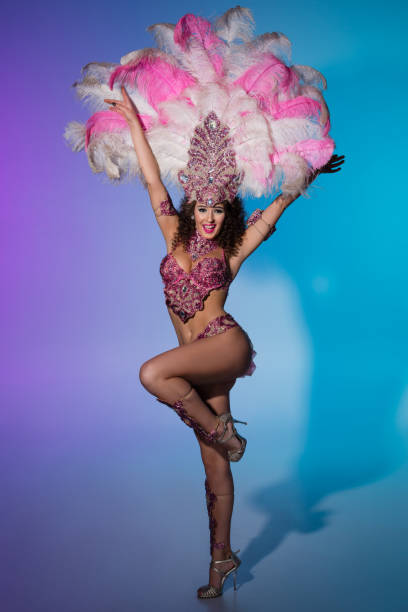 istock Bright woman in carnival costume with pink feathers performs 908557478