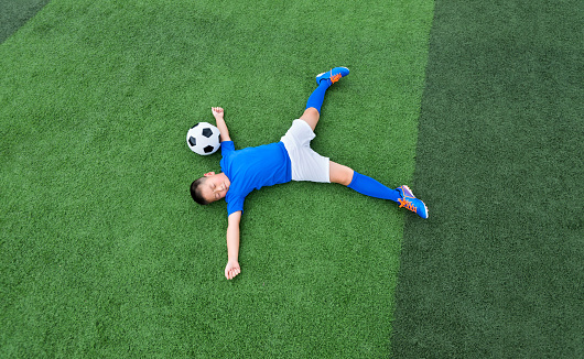 Young boy lying on soccer field