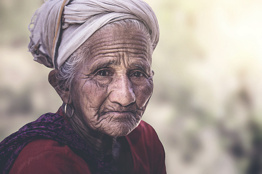 Old Indian/Asian woman with wrinkles elderly senior,  sitting outside her village home.