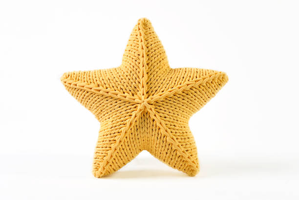 Yellow knitted five-pointed star shaped pillow on white background