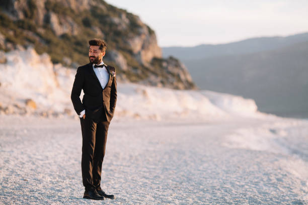 istock Groom posing for camera on the beach 908561988