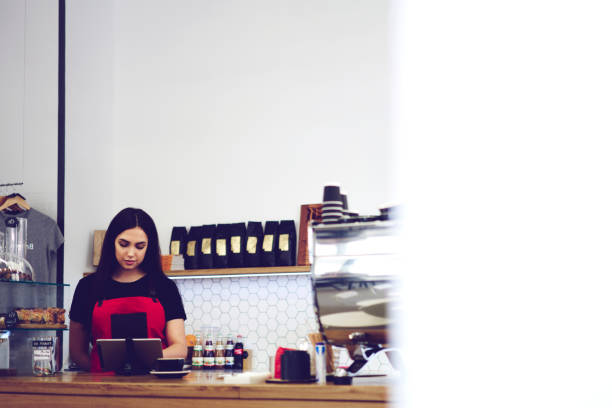 istock Concentrated serious waitress making online ordering in coffee shop using modern touch pad connected to wifi, administrative manager checking application for financial reporting and database 908564614