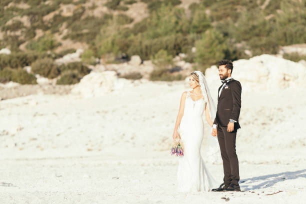 istock Bride and groom holding hand on the beach 908567730