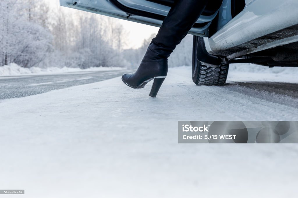 Routes in the winter, on the road the white car and the girl leg Car Stock Photo