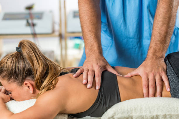 istock Physical therapy. Therapist applying strong pressure onto lower back muscles 908571622