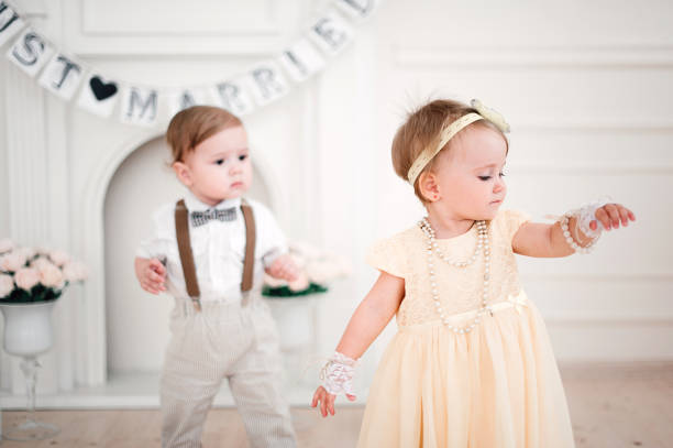 istock two babies wedding - boy and girl dressed as bride and groom 908581496