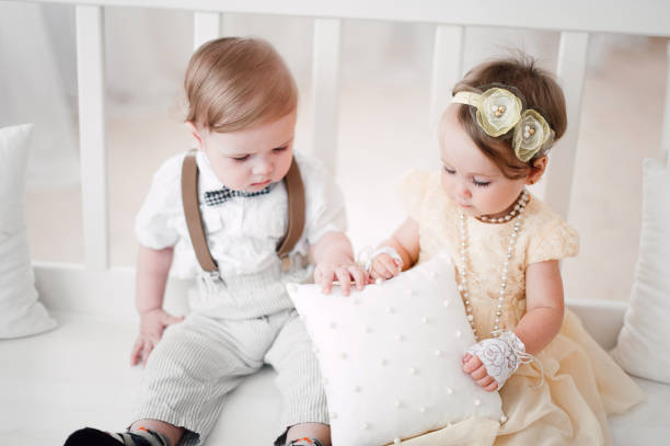 istock two babies wedding - boy and girl dressed as bride and groom 908581584