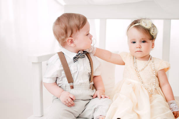 istock two babies wedding - boy and girl dressed as bride and groom 908581600