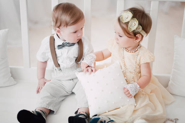 istock two babies wedding - boy and girl dressed as bride and groom 908581604