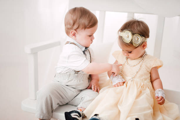 istock two babies wedding - boy and girl dressed as bride and groom 908581620