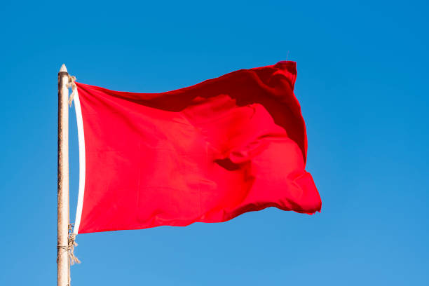 Old red flag and blue sky, red banner waving against blue sky stock photo
