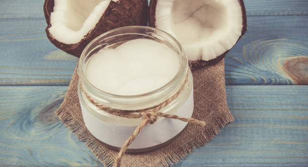 istock Coconut oil and fresh coconuts on a wooden table. 908590422