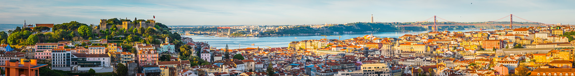 Warm sunlight of daybreak illuminating the colourful villas and crowded rooftops of central Lisbon, Portugal’s vibrant capital city.