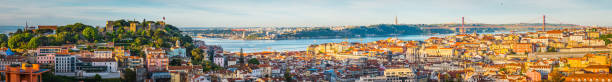 Lisbon sunrise super panorama across Castelo Baixa and bridge Portugal Warm sunlight of daybreak illuminating the colourful villas and crowded rooftops of central Lisbon, Portugal’s vibrant capital city. lisbon photos stock pictures, royalty-free photos & images