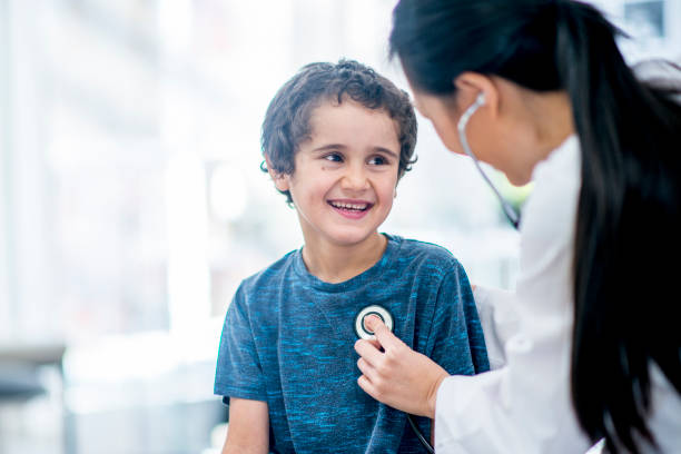 Checking Heart Rate A young boy is indoors in a hospital room. His female doctor is giving him a checkup. The boy is smiling while the doctor checks his heart rate with a stethoscope. taking pulse stock pictures, royalty-free photos & images