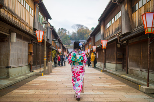 Young woman in kimono walking in traditional Japanese town