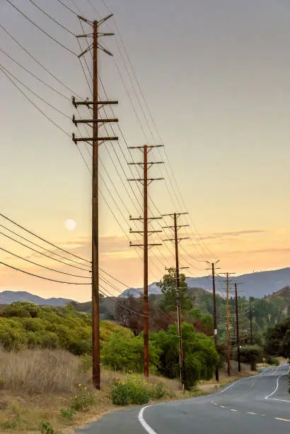 Photo of Utility poles run parallel to California highway, at sunset