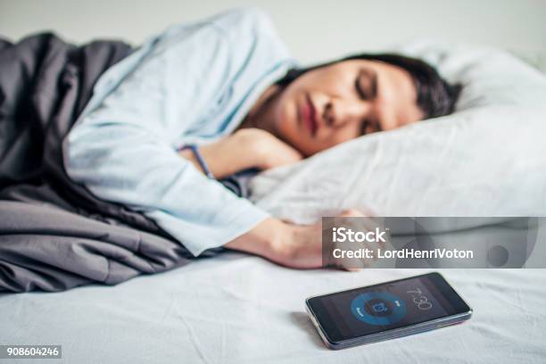 Woman Sleeping On Bed With Alarm On Mobile Phone Stock Photo - Download Image Now - Sleeping, Technology, Telephone