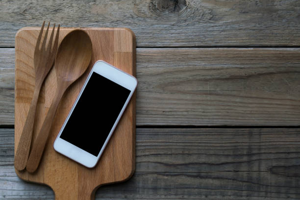 istock mobile phone served wiht fork and spoon on wood plate, concept and idea 908605384
