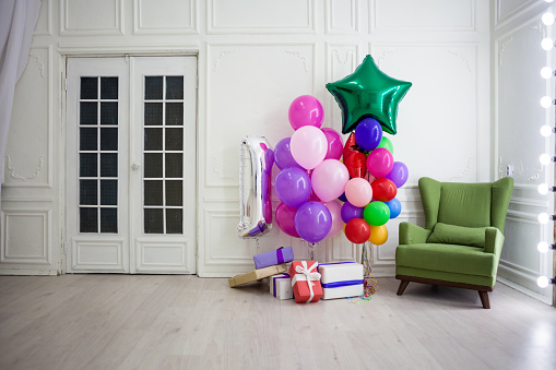 balloons of different colors with gifts for the holiday in a white room