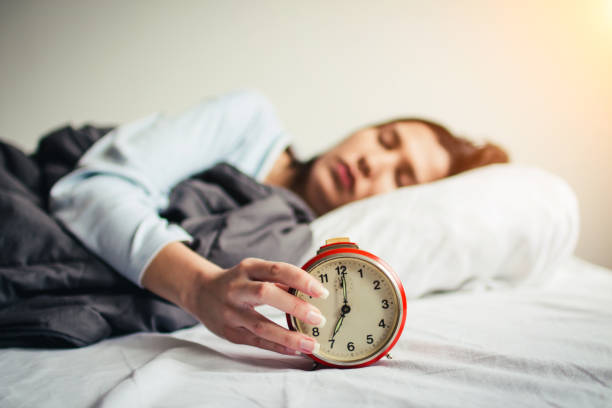 istock woman sleeping in  bed with alarm clock. 908605602