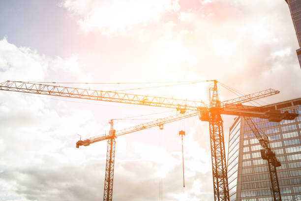 istock Abstract industrial background with construction cranes silhouettes over amazing sunset sky 908605946