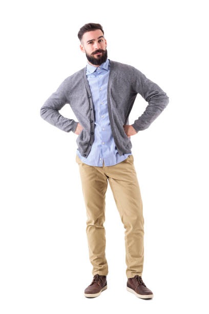 istock Skeptical young fashionable bearded man with arms on hips looking at camera 908610320