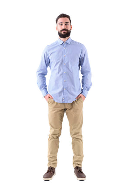 istock Front view of young beard smart casual business man with hands in pockets 908611564