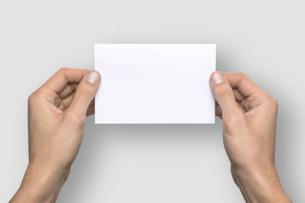 istock Empty white A6 postcard horizontally. Man holds a pattern in his hands on a gray background 908613984