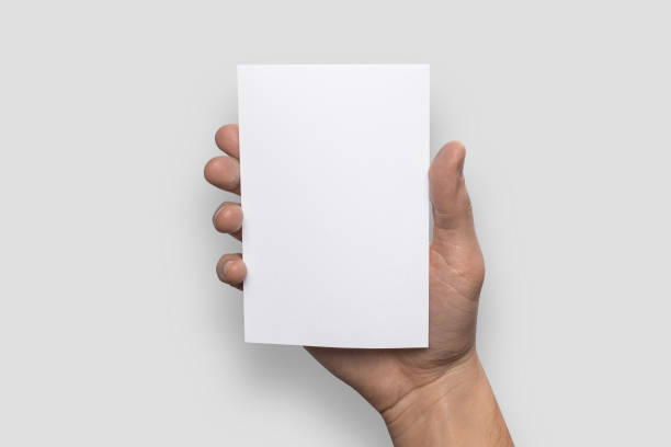 istock Empty white A6 postcard vertically. Man holds a pattern in his hand on a gray background 908614060