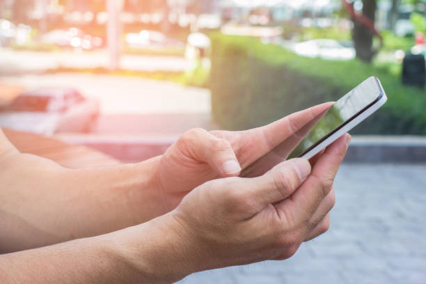istock Close up of men hands holding touching mobile phone with blank copy space for your text message at park with light Sunset,Vintage tone.Selective focus 908625690