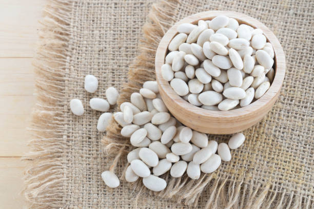 istock white bean in wood cup on sack background 908625766