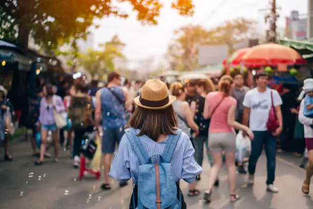 Photo of Young woman traveler with sky blue backpack and hat looking the way with in JJ Market in Bangkok Thailand. Traveling in Bangkok Thailand