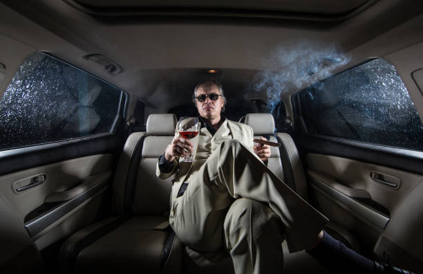 uomo ricco in un abito bianco in macchina, un milionario con un sigaro e un bicchiere di alcol - cigar whisky men smoking foto e immagini stock