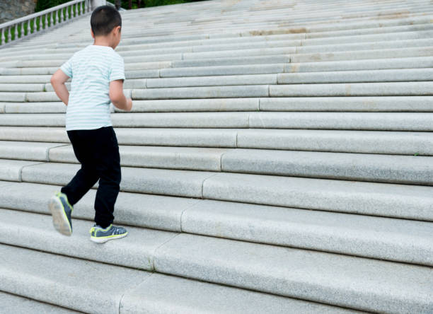 little boy climbing stairs outdoors - healthy lifestyle nature sports shoe childhood imagens e fotografias de stock