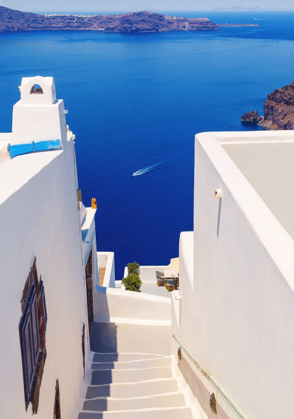 istock White architecture with steps leading down to the sea on Santorini island, Greece. Beautiful landscape with sea view. 908637408