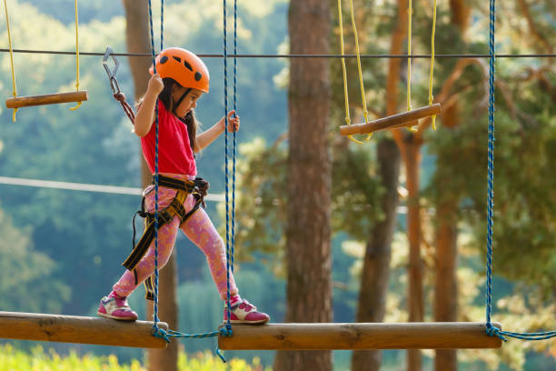retrato de um lindo menino e uma menina andar sobre uma ponte de corda em um parque de corda de aventura. - coragem - fotografias e filmes do acervo