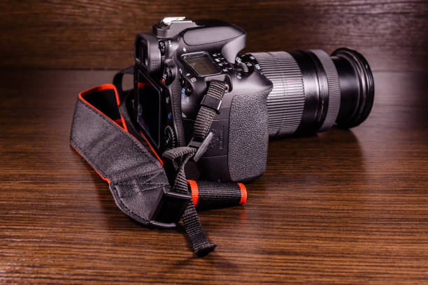 istock Modern dslr camera on the dark wooden table 908644216