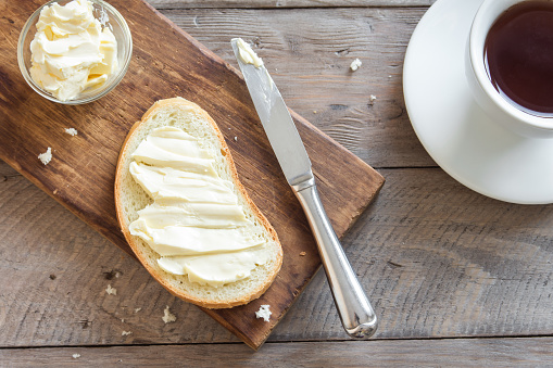 Butter and bread for breakfast, with cup of coffee over rustic wooden background with copy space. Morning breakfast with coffee, butter and toasts.