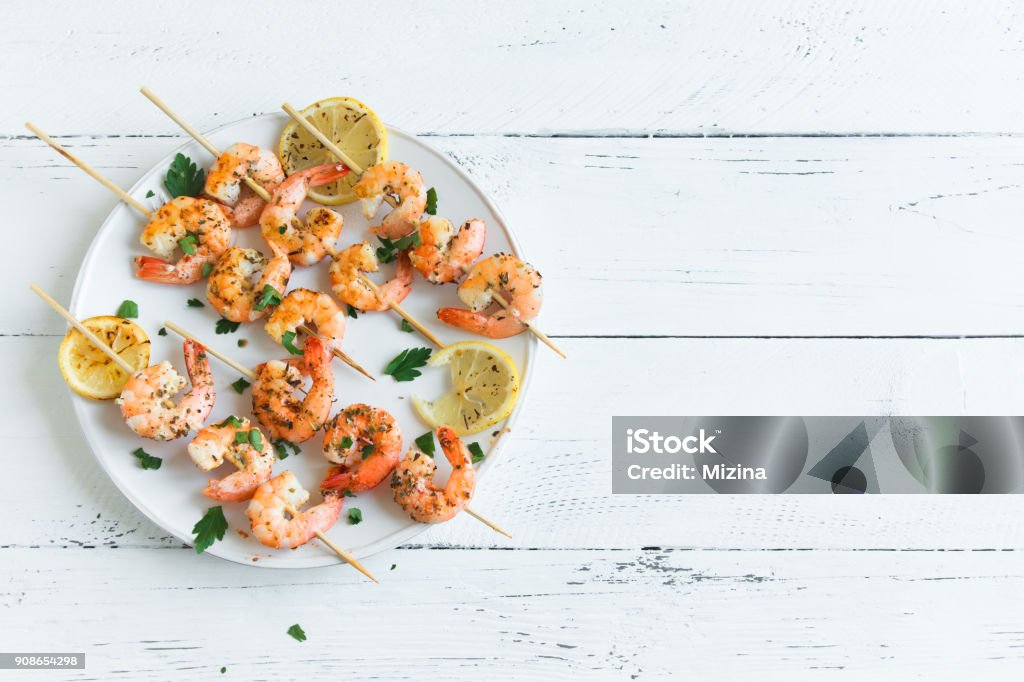 shrimp skewers Grilled shrimp skewers. Seafood, shelfish. Shrimps Prawns skewers with spices and fresh herbs on white wooden background, copy space. Shrimps prawns brochette kebab. Barbecue srimps prawns. Skewer Stock Photo