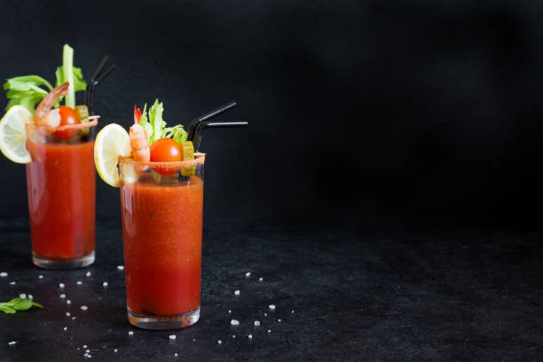 Bloody Mary Cocktail Bloody Mary Cocktail in glasses with garnishes. Tomato Bloody Mary spicy drink on black background with copy space. bloody mary stock pictures, royalty-free photos & images
