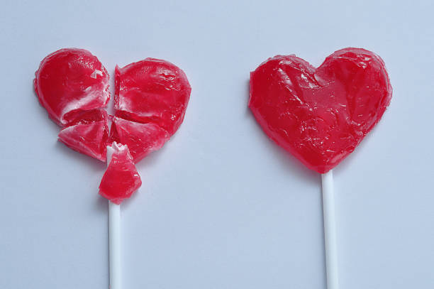 istock A broken red heart lollipop and a whole one symbolizing a relationship were one partner is heart broken 908660866