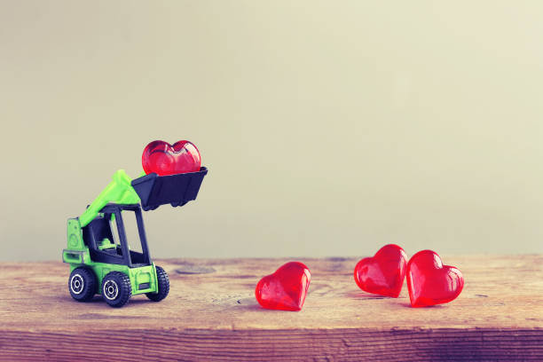istock Toy excavator loads heart on wooden table 908661124