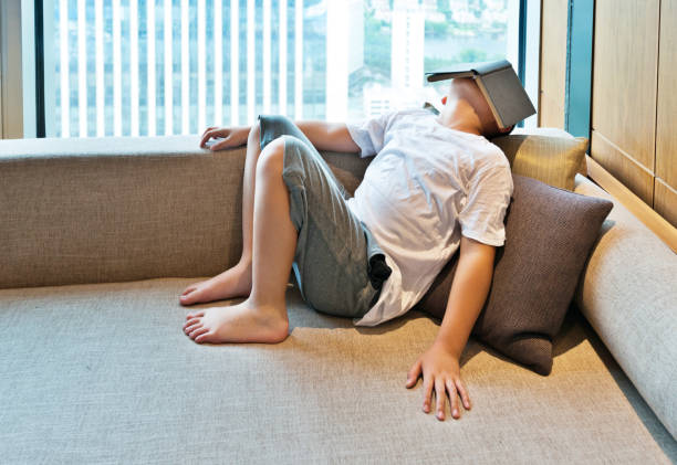 istock Little boy lying on the sofa with book 908662112