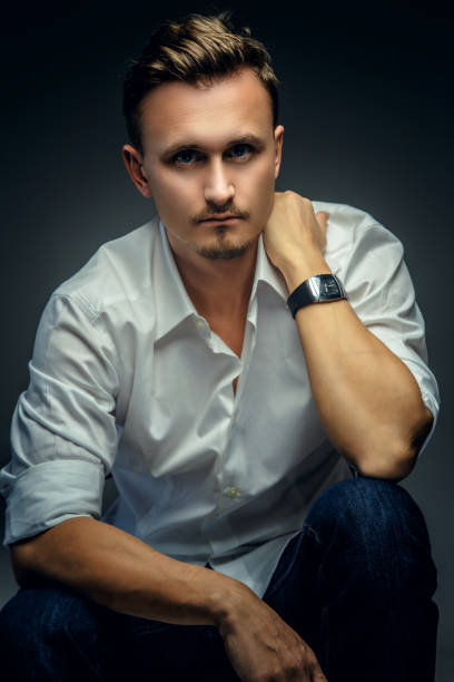 istock Elegant man in white shirt possing in studio. 908664518