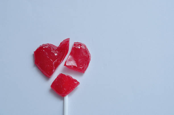 A broken red heart lollipop symbolizing a broken heart A broken red heart lollipop symbolizing a broken heart broken heart stock pictures, royalty-free photos & images