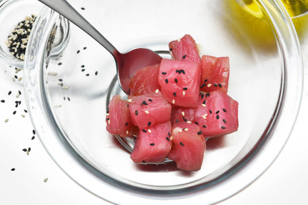 preparing tuna for Hawaiian ahi poke bowl with sesame seeds and soy sauce
