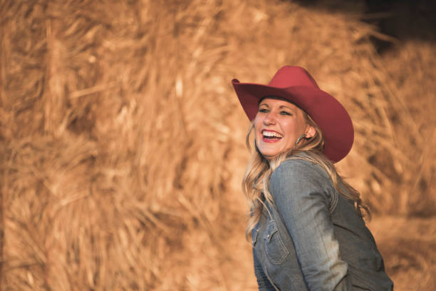 istock Standing by a haystack, a happy cowgirl is having fun. 908670904