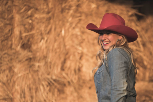 istock Standing by a haystack, a happy cowgirl is having fun. 908670908