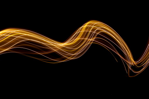Long exposure photograph of metallic gold fairy lights, in a range of golden tones against a black background